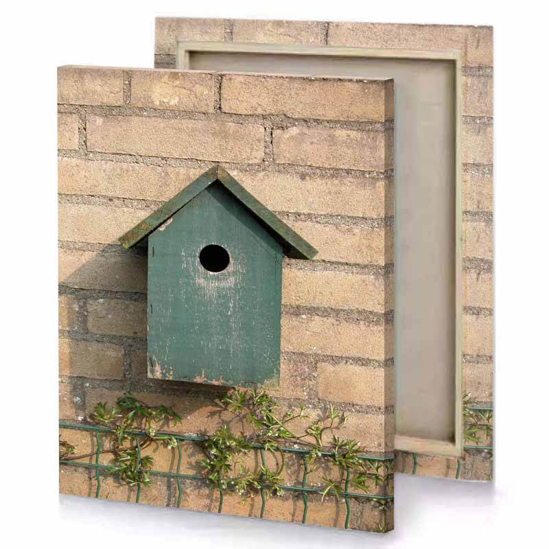 a bird house on fence in front of brick wall camouflage green canvas