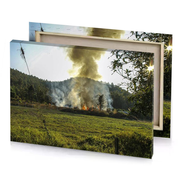 a fire is burning in field with house the background camouflage green canvas