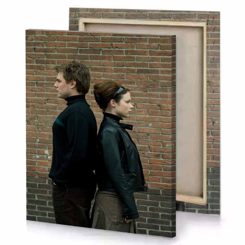 a man and woman standing next to brick wall dark olive green canvas