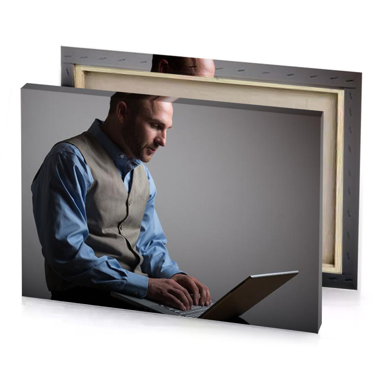 a man sitting down on laptop computer gray canvas