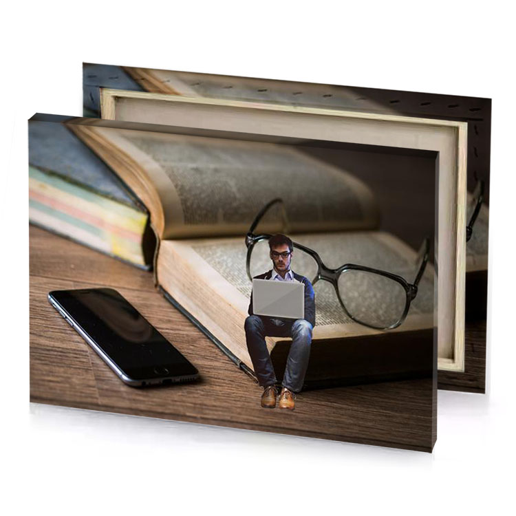 a miniature man sitting on book with laptop tan canvas