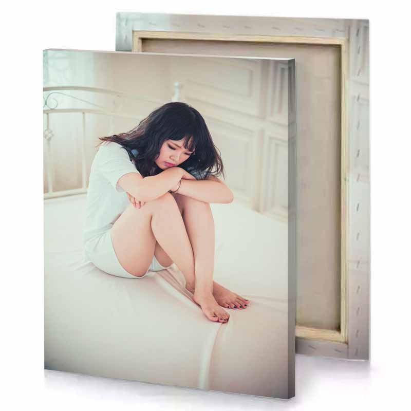 a woman sitting on bed with her head knees silver canvas
