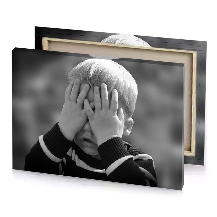 a young boy covers his face with hands gray canvas