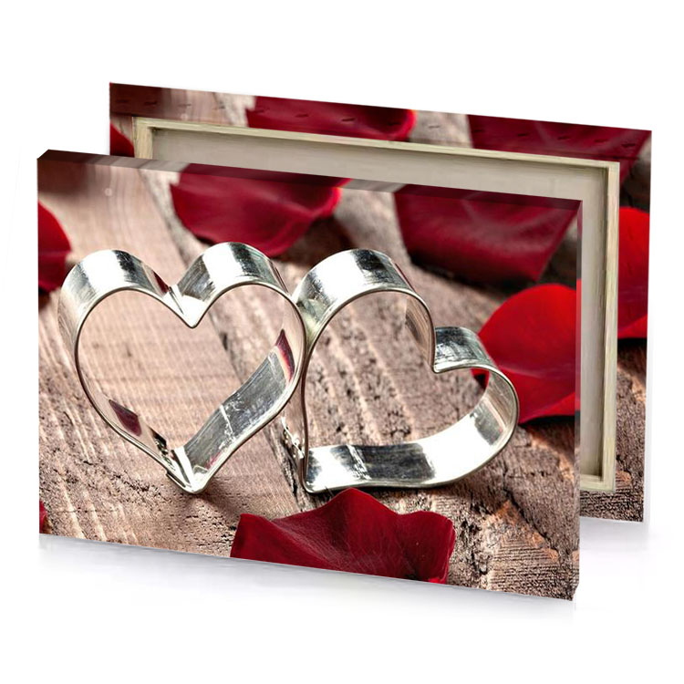 two silver hearts on a wooden surface surrounded by red canvas