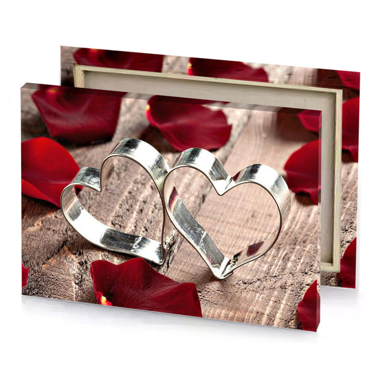 two silver hearts on a wooden table surrounded by red canvas