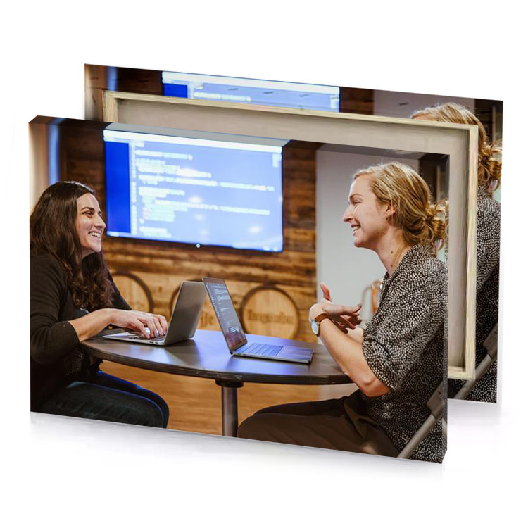two women sitting at a table with laptop zinnwaldite brown canvas